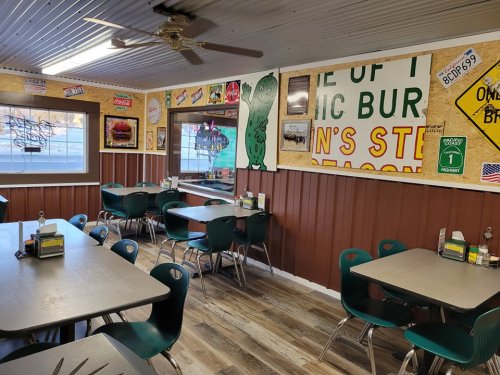 A cozy diner interior with green chairs, wooden walls, and vintage signs decorating the space.