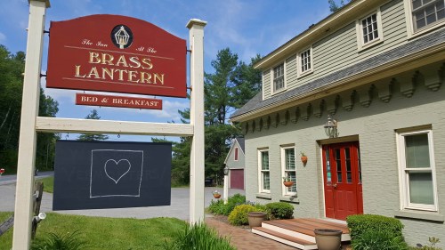 Sign for "The Inn at the Brass Lantern" Bed & Breakfast, featuring a heart on a chalkboard and a charming exterior.