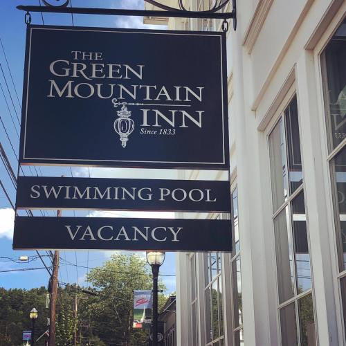 Sign for The Green Mountain Inn featuring "Swimming Pool" and "Vacancy" below, with a clear blue sky in the background.