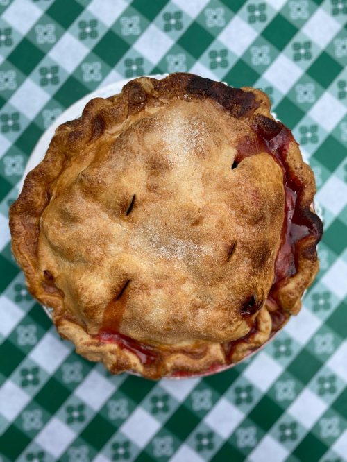 A golden-brown pie with a flaky crust, resting on a green and white checkered tablecloth.