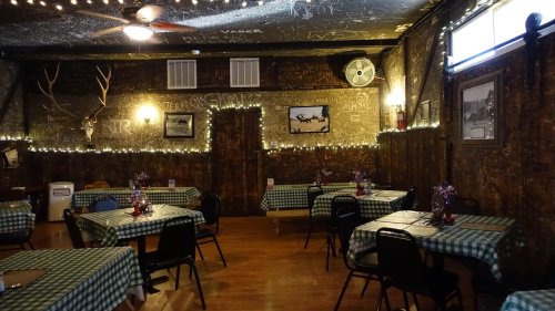 Cozy restaurant interior with checkered tables, string lights, and chalkboard walls, creating a rustic atmosphere.