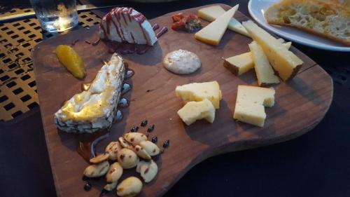 A wooden cheese board featuring various cheeses, nuts, fruit preserves, and a drizzle of honey.