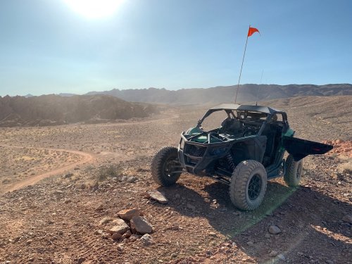 A rugged off-road vehicle parked on a rocky terrain with mountains in the background under a clear blue sky.
