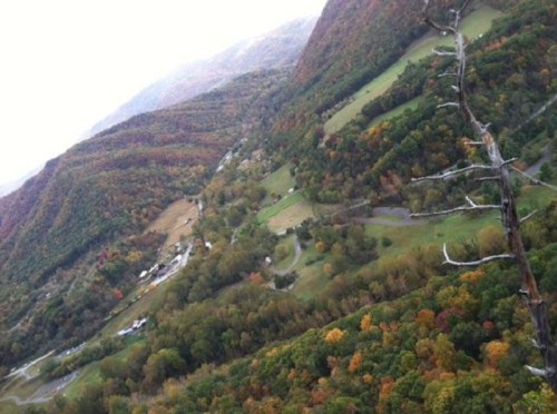 Aerial view of a lush valley surrounded by colorful autumn foliage and rolling hills.