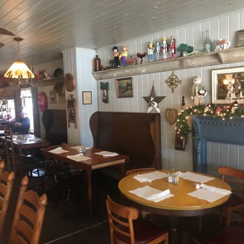 Cozy restaurant interior with wooden tables, festive decorations, and a vintage charm.
