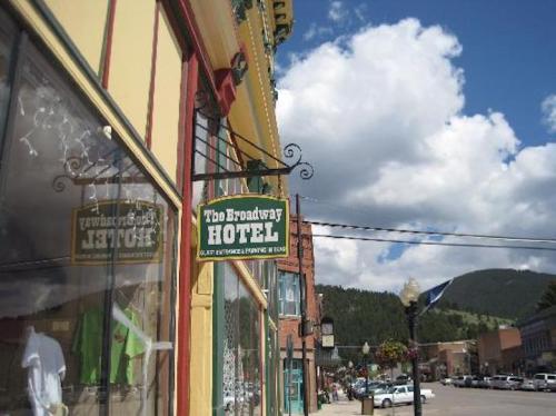 Sign for The Broadway Hotel hangs outside a colorful building, with a blue sky and clouds in the background.