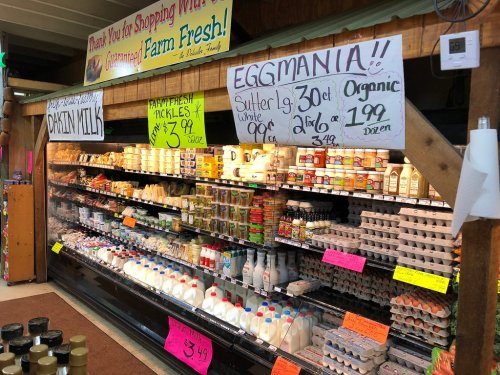 A grocery store display featuring dairy products, eggs, and pickles with colorful signs and prices.