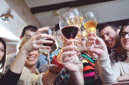 A group of friends raising glasses filled with various drinks in a celebratory toast.