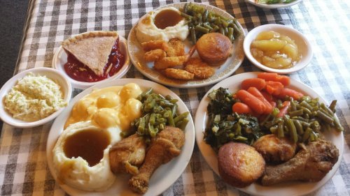 Two plates of Southern-style comfort food featuring fried chicken, greens, mashed potatoes, cornbread, and pie.