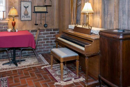 A cozy room featuring a wooden piano, a table with a red tablecloth, and warm lighting from lamps.
