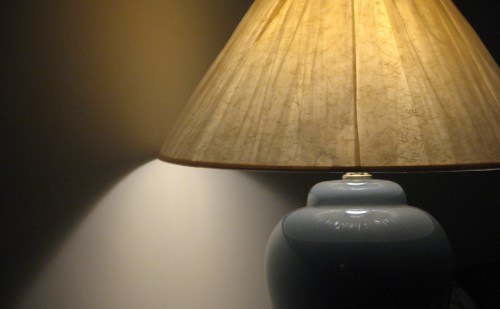 A blue lamp with a textured shade casts a warm glow against a wall.