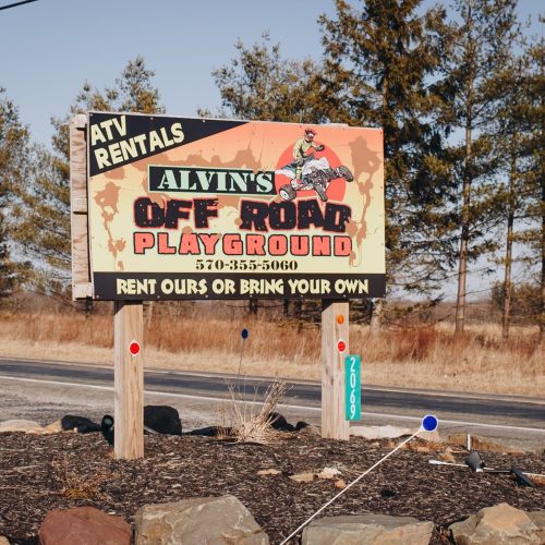 Sign for Alvin's Off Road Playground offering ATV rentals, with contact number and rental options displayed.