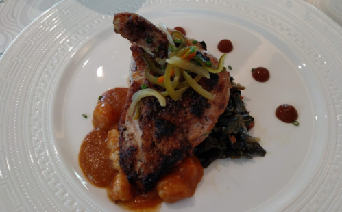 Grilled chicken breast topped with green peppers, served on a bed of greens and accompanied by sauce and dumplings.