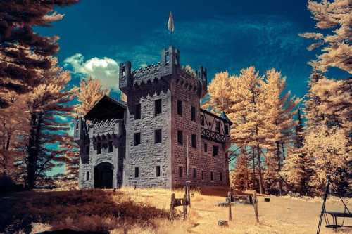 A stone castle surrounded by vibrant trees under a bright blue sky, creating a surreal, dreamlike atmosphere.