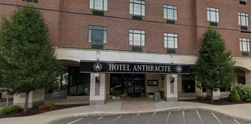 Exterior view of Hotel Anthracite, featuring a brick facade and entrance with greenery on either side.