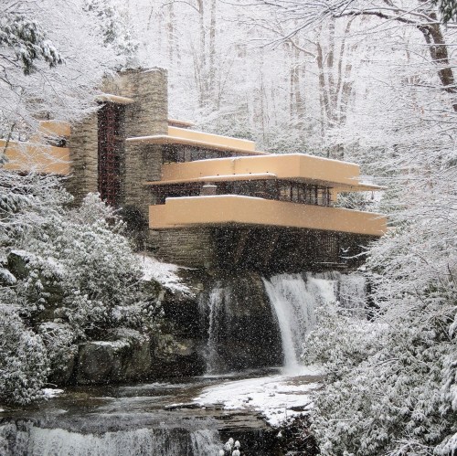 A modernist house with cantilevered balconies, surrounded by snow-covered trees and a waterfall.