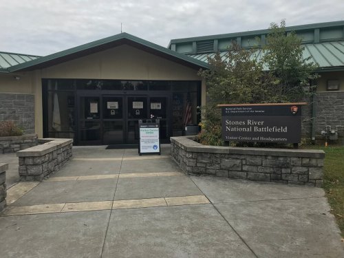 Entrance to Stones River National Battlefield Visitor Center, featuring stone walls and a sign.