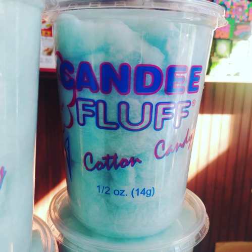 A clear cup filled with blue cotton candy, labeled "Candee Fluff" with a playful design.