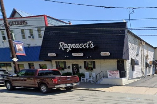 A restaurant named "Ragnacci's" with a black roof and outdoor seating, located on a sunny street.