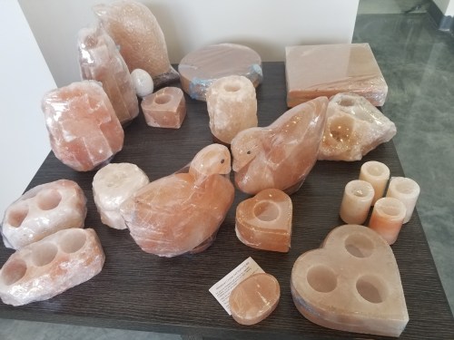 A table displays various carved salt items, including candles, a duck, and a heart shape, all wrapped in plastic.