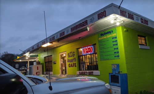A brightly colored café with a neon "OPEN" sign, featuring a menu of burgers, BBQ, and hot dogs.