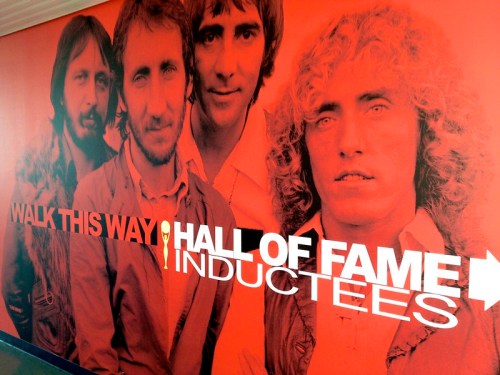 A mural featuring four musicians with the text "Walk This Way Hall of Fame Inductees" on a bright red background.