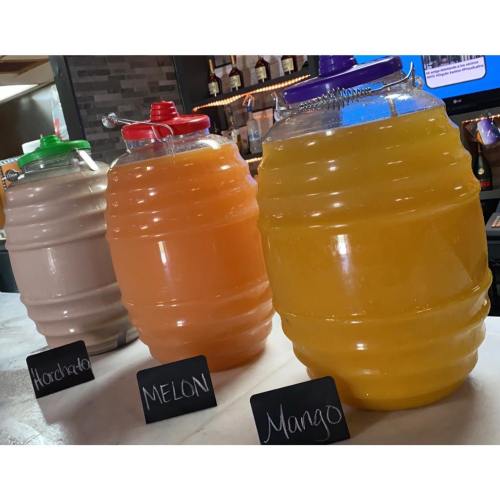 Three large beverage dispensers filled with horchata, melon, and mango drinks, labeled on a bar counter.