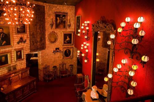 A richly decorated room with red walls, vintage portraits, ornate mirrors, and elegant lighting fixtures.