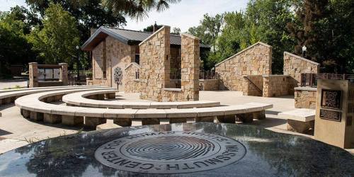 A stone plaza with curved seating and a building, featuring a circular emblem for the Center for Human Rights.