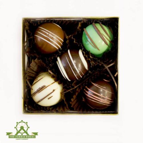 A box of four decorative chocolate truffles in various flavors, elegantly arranged with decorative liners.
