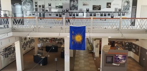 Interior view of a museum exhibit featuring historical displays and a flag hanging from the balcony.