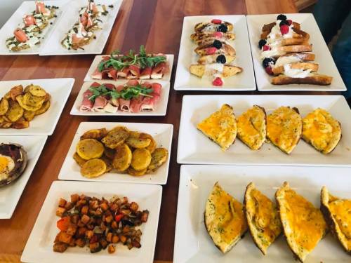 A variety of beautifully arranged dishes on white plates, including appetizers, baked goods, and roasted vegetables.