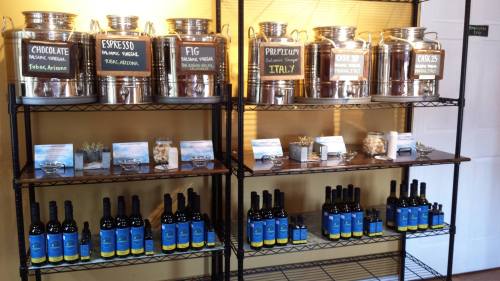 Shelves displaying various balsamic vinegars and oils, with labeled containers and tasting samples.