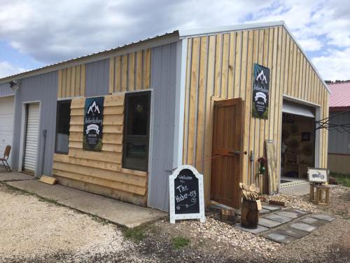 A rustic wooden building with a gray and natural wood exterior, featuring a welcoming sign and decorative banners.
