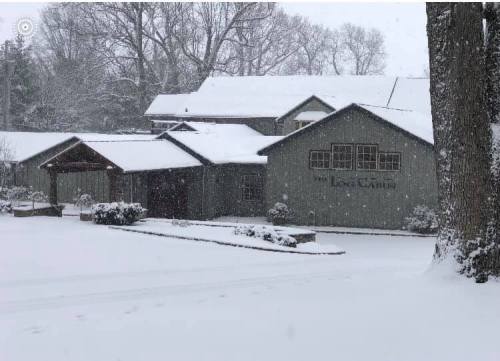 A snow-covered building with a sign reading "Long Cabin," surrounded by trees and a snowy landscape.