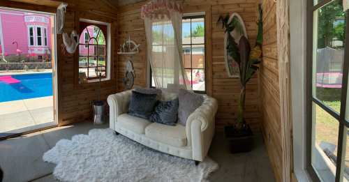 Cozy interior with a white couch, plush rug, and large windows overlooking a pool area.