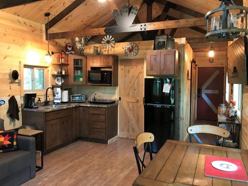 Cozy cabin interior featuring a kitchen, dining area, and rustic decor with wooden accents and warm lighting.