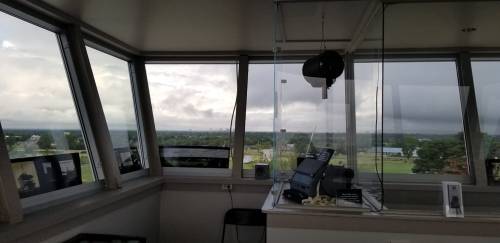 View from an airport control tower, featuring equipment and a cloudy sky in the background.