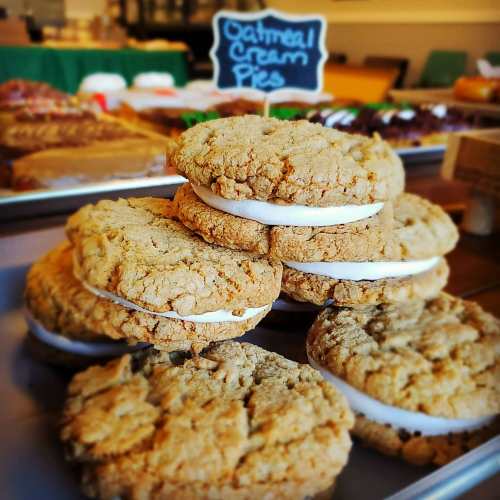 A stack of oatmeal cream pies with a small sign in the background, showcasing a variety of baked goods.