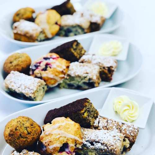 Three plates of assorted baked goods, including muffins and pastries, garnished with dollops of cream.