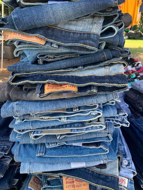 A tall stack of various denim jeans folded neatly, showcasing different shades of blue and styles.