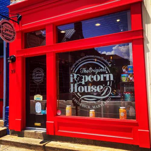 Bright red storefront of The Original Popcorn House in Frederick, Maryland, featuring large windows and popcorn displays.