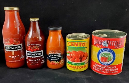 Five jars and cans of tomato products, including sauces and whole tomatoes, displayed on a black background.