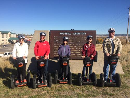 Five people on Segways pose in front of a sign for Boothill Cemetery on a sunny day.
