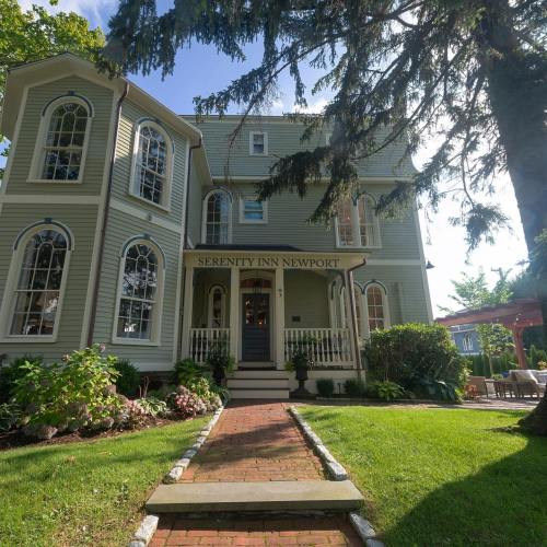A charming Victorian-style inn with a welcoming porch, surrounded by lush greenery and a stone pathway.