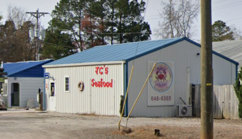 A seafood restaurant with a blue roof and sign reading "JC's Seafood," located in a rural area.
