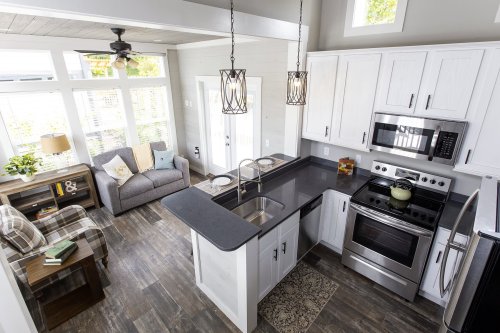 A modern kitchen with stainless steel appliances, a cozy living area, and large windows letting in natural light.