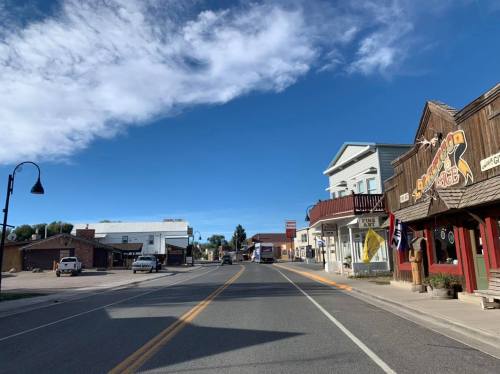 A quiet main street in a small town, featuring shops and clear blue skies.