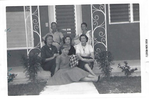 A group of six people sitting on steps in front of a house, smiling, in Florida, November 1954.