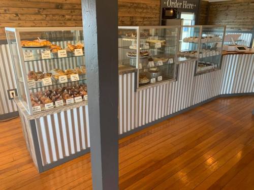 Display case filled with various baked goods in a rustic café setting, featuring wooden floors and a cozy atmosphere.